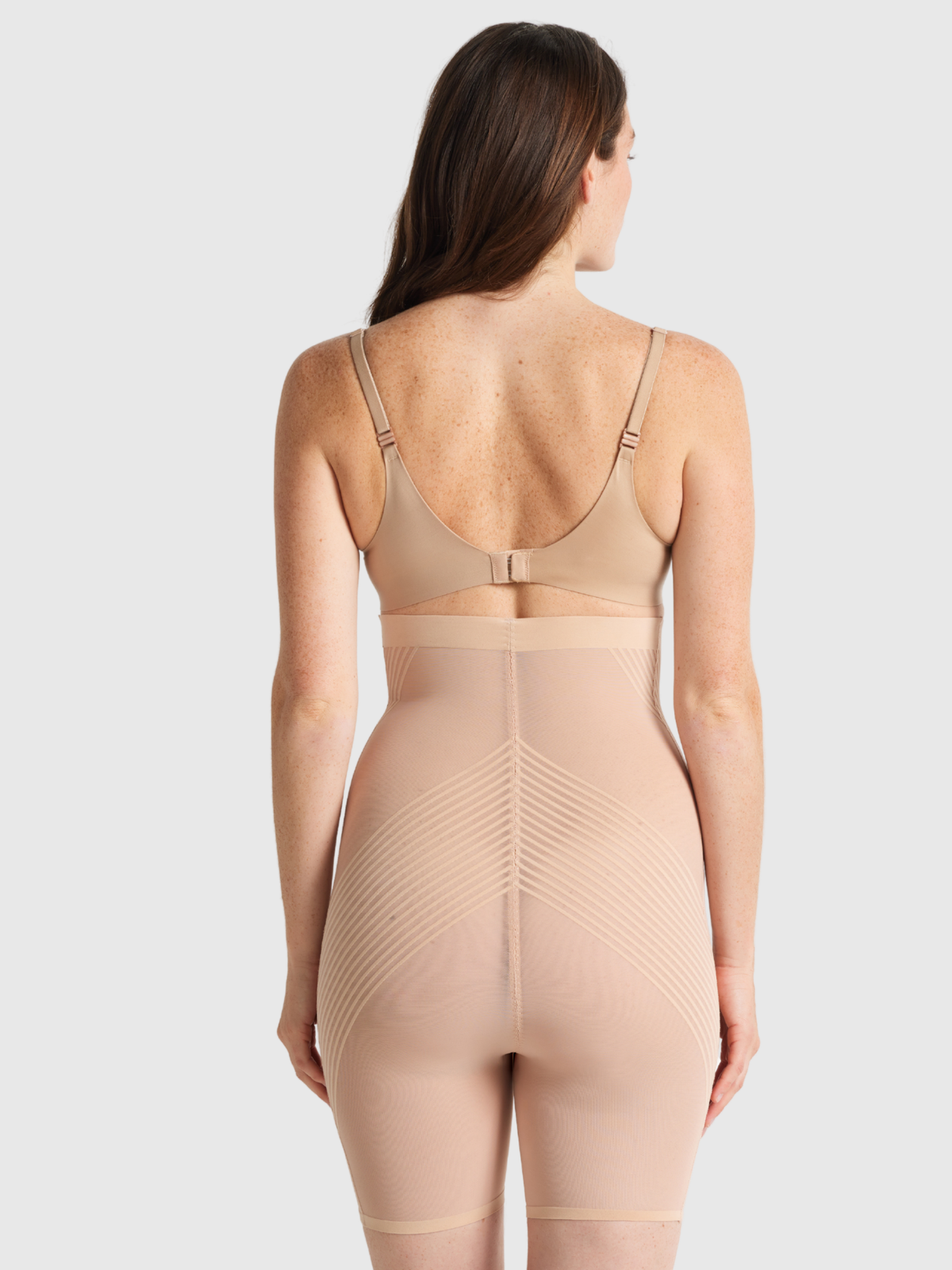 Nancy Ganz Sheer Power High Waisted Thigh Shaper in warm taupe, back view showing sheer panelling across the seat and smooth leg hems