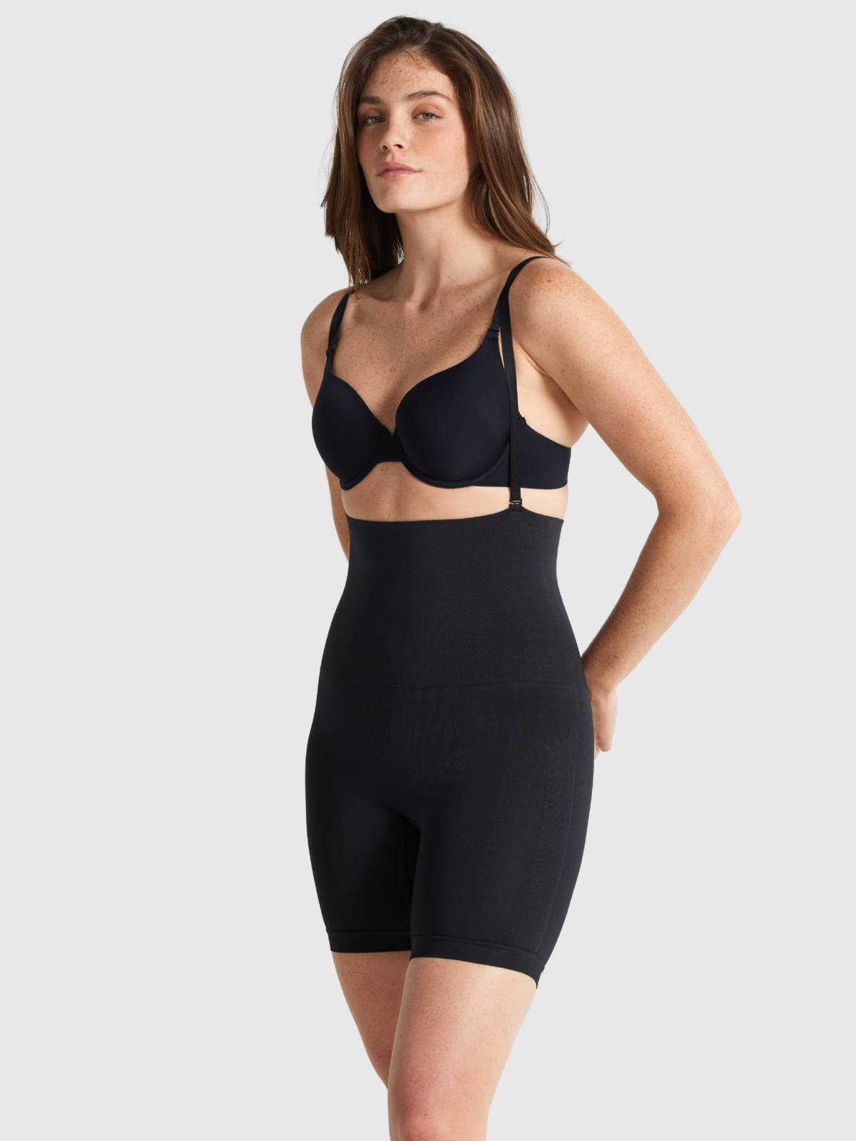 Nancy Ganz Seamless Seduction high waisted thigh shaper in Black, side view with support straps on, mid-thigh leg length