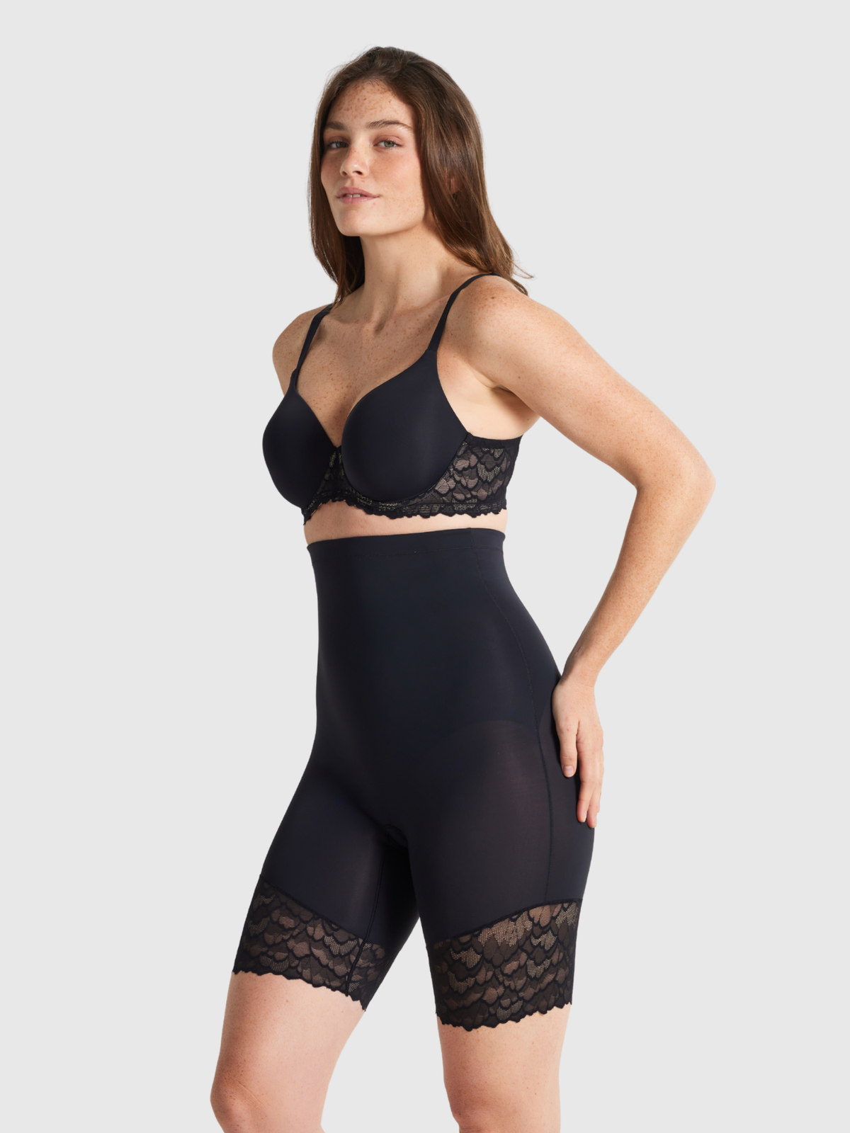 Nancy Ganz Sculpted Lace High Waisted Thigh Shaper in black, side view showing high rise waistband and lace-trimmed leg extending down the thigh.
